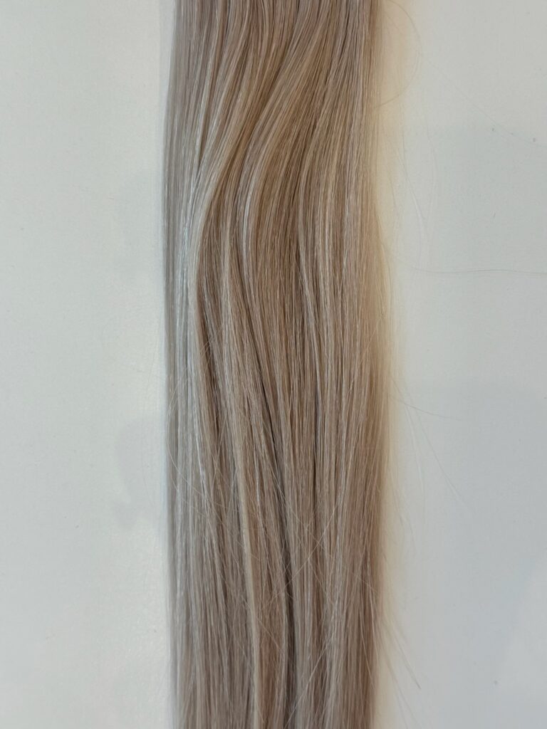 A close-up of Avery—a straight, light brown hair product with subtle highlights—styled in smooth, wavy strands against a plain white background.