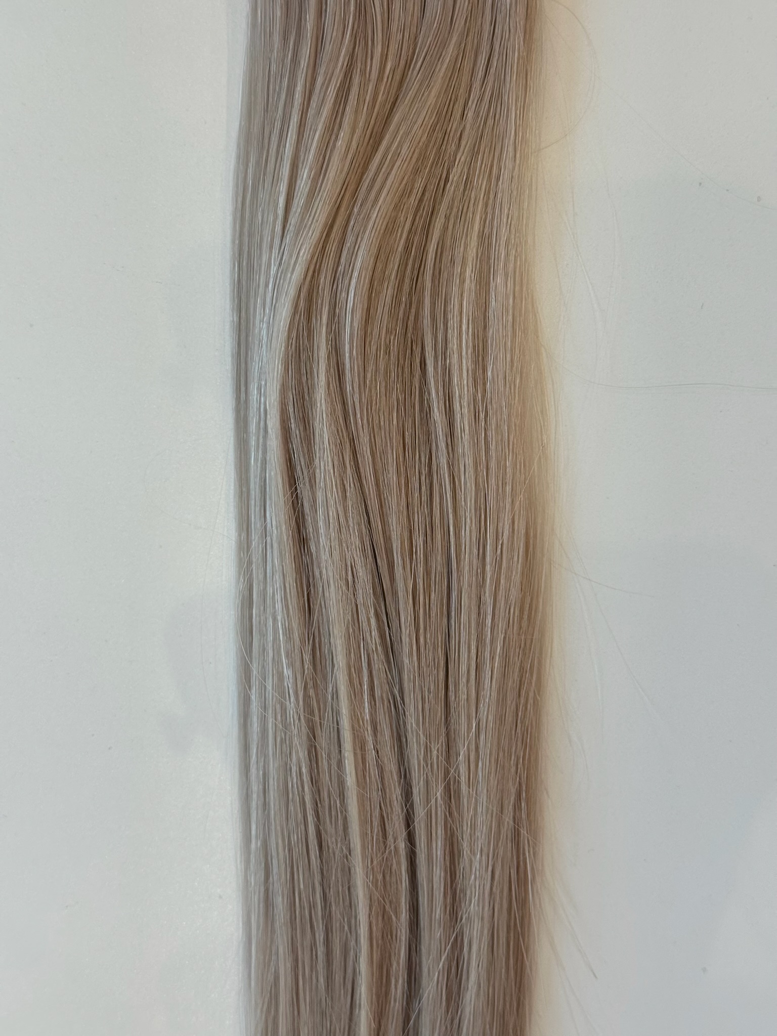 A close-up of Avery—a straight, light brown hair product with subtle highlights—styled in smooth, wavy strands against a plain white background.