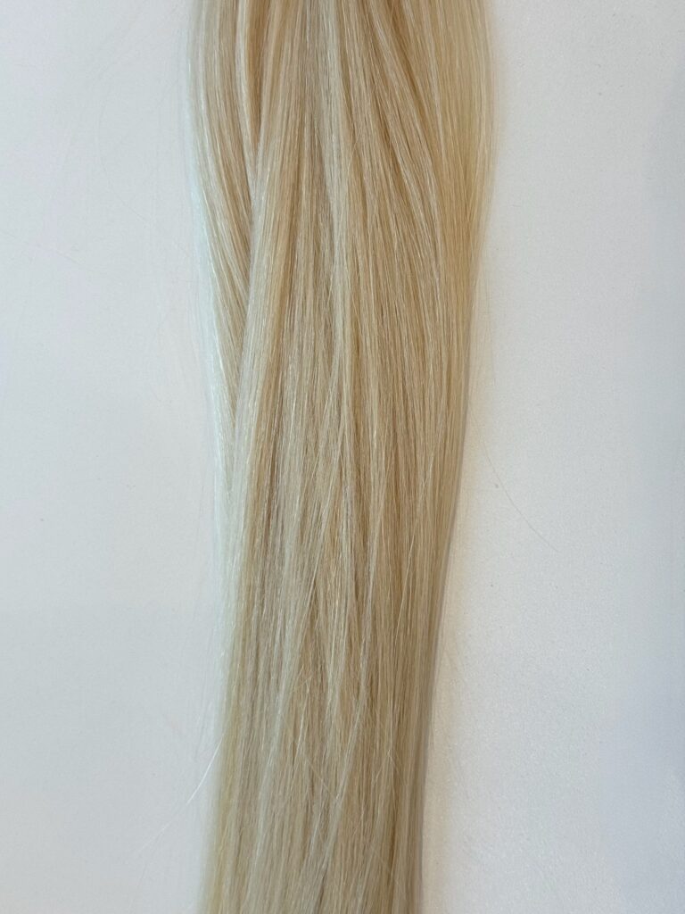 A long strand of straight, light blonde Frannie hair lies against a plain white background.
