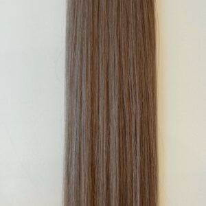 A close-up of Jessica's straight, light brown hair strands laid flat against a neutral, off-white background.