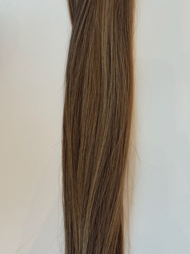 A close-up of Joli straight, light brown hair with subtle highlights, shown against a plain white background.