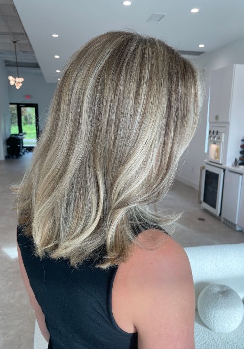 Blonde hair with highlights styled in a low cut, showcased in an elegant boutique salon setting.