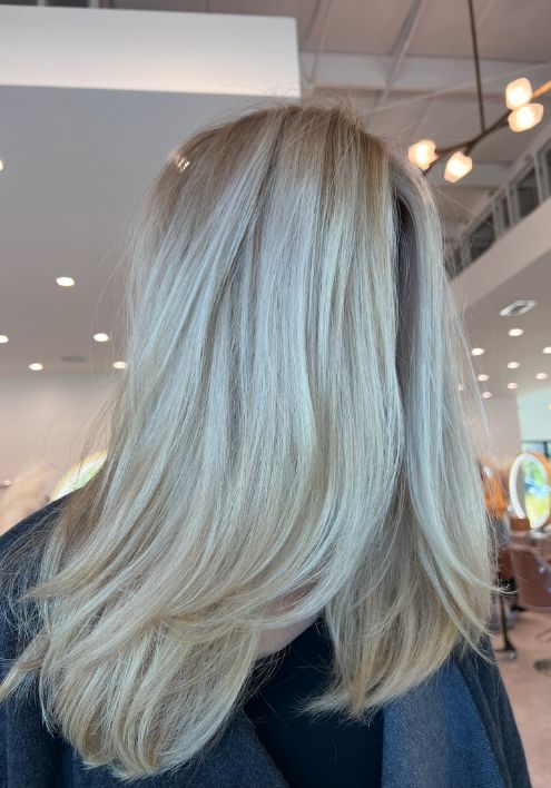 A blonde woman with long hair is being styled at Luxe Artist Salon, showcasing a luxurious salon atmosphere.