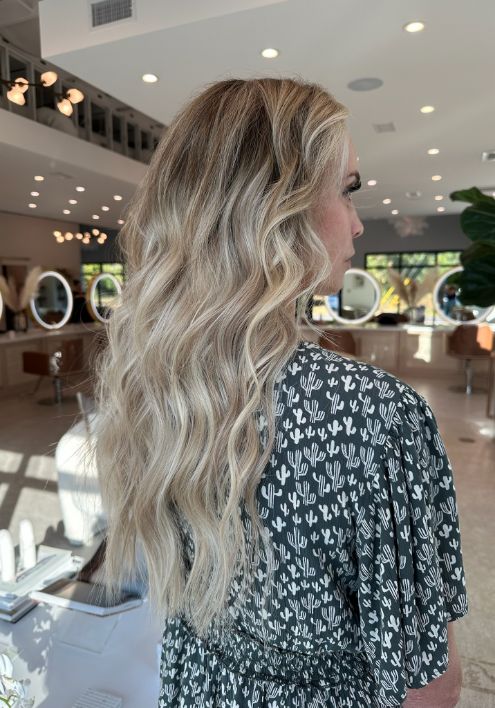 A woman with long blonde hair enjoys a luxurious salon experience using Virtue Products.